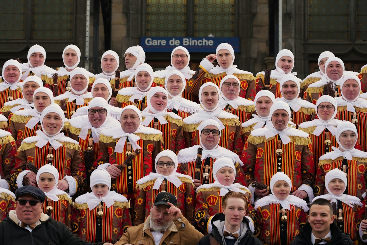 Gruppe von kostümierten Darstellern, die vor einem Steingebäude posieren.