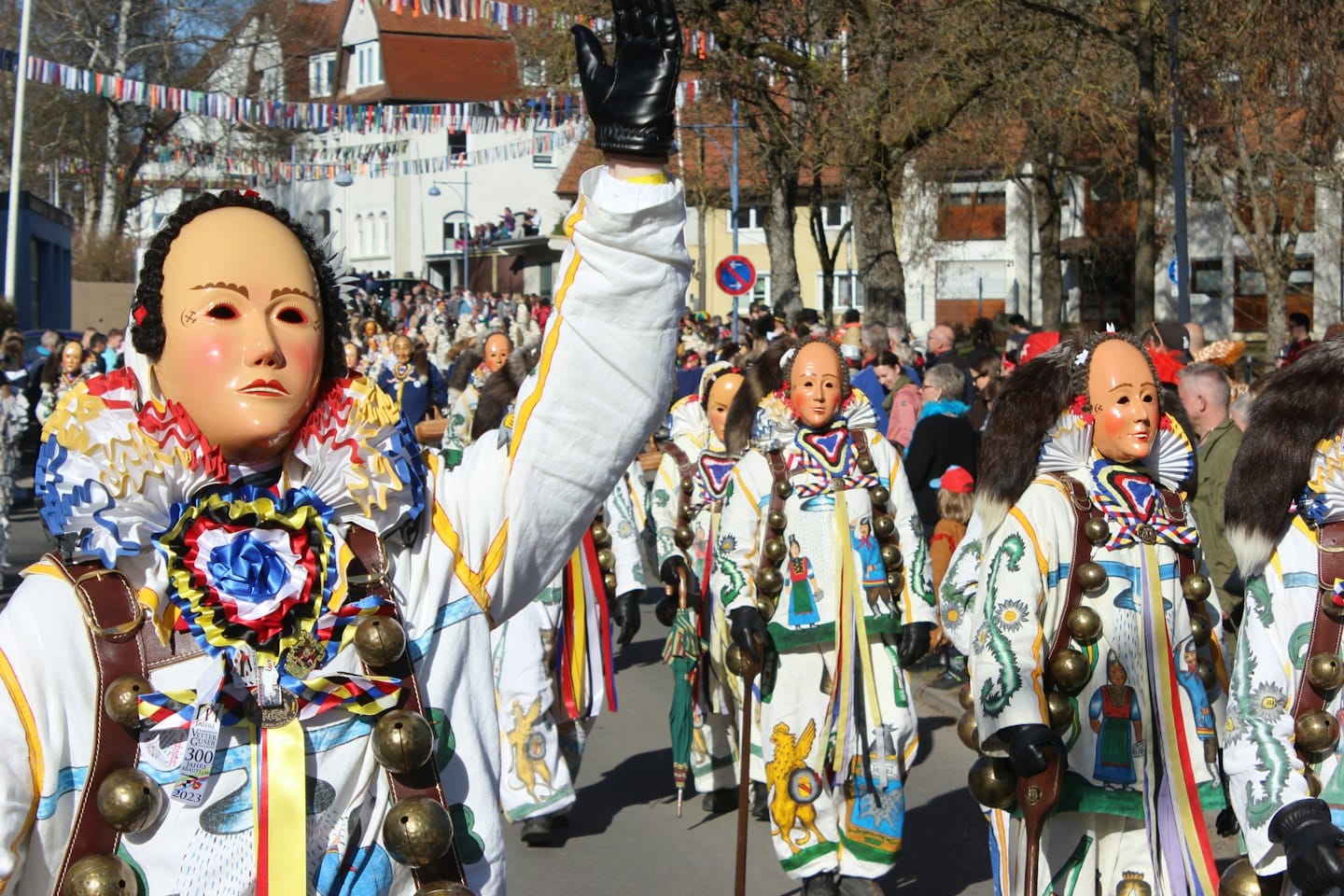 Schwäbisch-alemannische Fasnetsnarren mit Holzmasken ziehen durch eine Straße.